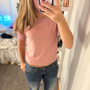 Rosa stickad tröja från H&M - Säljer en söt rosa stickad tröja från H&M Basics. Tröjan har korta ärmar, rund halsringning och ribbade muddar vid ärmslut och nederkant. Perfekt till jeans eller kjol för en chill och stilren look.