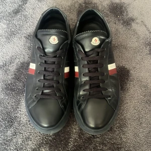 Svarta Moncler sneakers i skinn - Snygga svarta sneakers från Moncler. Storlek- 41. Skick- 7,5/10, lite skrynkliga på vissa ställen. Tveka inte vid frågor.