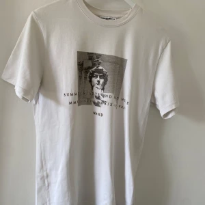Vit t-shirt med print - Vit t-shirt från NA-KD x Summerburst, med svartvit grafiskt print framtill. Strl xs men oversized så sitter bra på mig som s/m. Skön och enkel modell i bomull.