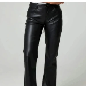 Svarta bootcut byxor i skinnimitation - Snygga svarta byxor i skinnimitation med bootcut-snitt. De har klassisk femficksdesign och stängs med knapp och dragkedja. Perfekta för dig som vill ha en edgy och trendig look.