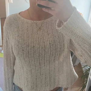 Beige stickad croppad tröja - Säljer en beige stickad tröja med croppad passform och rund hals. Tröjan har ett luftigt stickat mönster och långa ärmar, perfekt att styla med jeans eller kjol. Enkel och chill vibe, passar dig som gillar en avslappnad look.