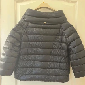 Herno liknande jacka  - Säljer en grå Herno liknade jacka med trekvartsärm. Jackan har knäppning framtill och är quiltad med breda kanaler. Perfekt för kyliga dagar när du vill ha något lätt men ändå varmt.