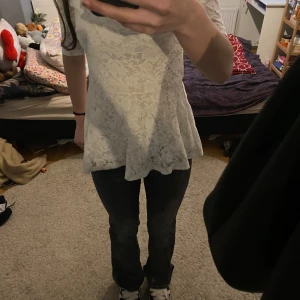 Vit spetsblus från Gina Tricot - Säljer en super söt vit topp  från Gina Tricot i spets med blommigt mönster. Blusen har korta ärmar, rund halsringning och en lätt utsvängd nederdel. Använt 2 tillfällen och är som nytt skick perfekt för sommaren 