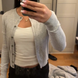 HM Ljusgrå kofta med knappar  - Säljer en ljusgrå från HM, tunn och mjuk kofta med rund hals och knäppning framtill. Perfekt att slänga över en topp eller linne. Enkel och stilren design som passar till det mesta.