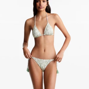 Ljusgrön blommig bikini från Mango - Säljer en ljusgrön bikini med vitt blommönster. Helt ny i originalförpackning, säljer då jag missade att lämna tillbaka. Nypris 400kr och storlek M (står L men det är Mango teen så L=M)