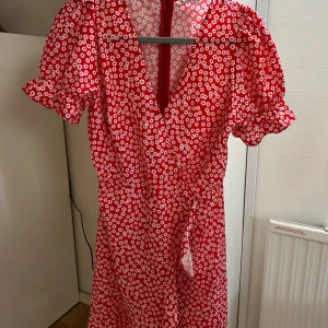 Röd blommig klänning från Chiquelle - Superfin röd klänning från Chiquelle med vita småblommor, v-ringning och puffärmar. Jättesöt till sommaren!🙏🏻