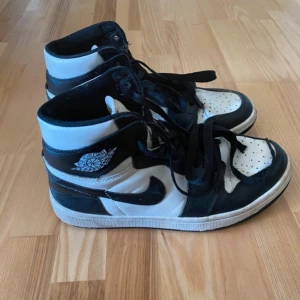 Nike Air Jordan 1 svartvita sneakers - Säljer ett par klassiska Nike Air Jordan 1 sneakers i svart och vitt. Skorna har högt skaft, snörning. Använda, men i bra skick! Storlek 41 men sitter som 40.
