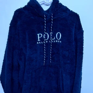 Mörkblå fluffig hoodie från Polo Ralph Lauren - Säljer en supermjuk och fluffig mörkblå hoodie från Polo Ralph Lauren. Tröjan har huva med dragsko och broderad logga framtill. Perfekt för dig som vill ha något riktigt bekvämt och snyggt till vardags.