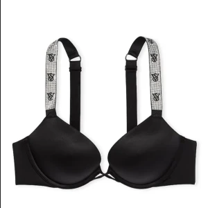 Svart push-up bh med glittriga axelband från vs - Säljer en svart push-up bh från vs med glittriga axelband dekorerade med logga. Bh:n har vadderade kupor och justerbara band för perfekt passform. Perfekt för dig som vill ha något extra snyggt under kläderna.