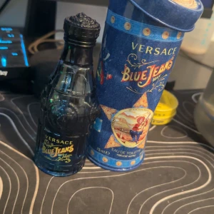 Versace Blue Jeans Edt - Versace Blue Jeans är en klassisk herrparfym med fräsch och maskulin doft. Ungefär 50ml är kvar. Flaskan är blå och har en unik design med detaljer i relief. Kommer i en blå metalltub med färgglada motiv och guldtext. Perfekt för dig som gillar ikoniska dofter. OBS förpackningen är lite pressad. 