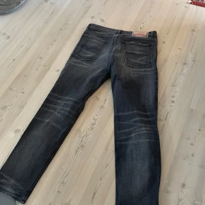 Svarta jeansbyxor från Diesel Industry - Säljer ett par svarta jeansbyxor från Diesel Industry med snygga slitningar och klassisk femficksdesign. Jeansen har raka ben och subtila detaljer som ger en cool, använd look. Perfekta för dig som gillar streetwear och tidlös denim. Använda 1 gång köpta för 2000