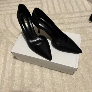 Svarta pumps med spetsig tå från shein - Säljer ett par eleganta svarta pumps från shein med spetsig tå och hög klack. Skorna är i syntetmaterial och har en klassisk, stilren design som passar perfekt till många olika outfits.