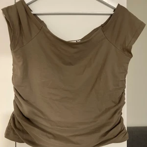 Beige offshoulder topp - Säljer en beige offshoulder topp i mjukt bomullsmaterial. Toppen har en avslappnad passform och är perfekt för varmare dagar. Enkel och stilren design som passar till mycket.