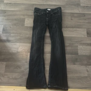 Svarta bootcut jeansbyxor från Gina Tricot - Svarta lågmidjade jeansbyxor från Gina Tricot med vita kontrastsömmar och bootcut-ben. Byxorna har fickor med lock och knapp både fram och bak samt klassisk knappgylf. Perfekta för dig som gillar en retroinspirerad look. Pris kan sänkas! Skriv för fler bilder. Använda 1-3 gånger💓jag är 158 och längden är perfekt 