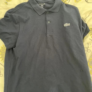 Mörkblå pikétröja från Lacoste - Ny skick passade inte.