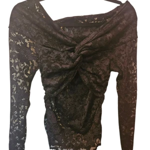 Svart spets topp med knutdetalj - Säljer en svart långärmad topp i spets med snygg knutdetalj framtill. off shoulder, använd fåtal gånger. Skriv för fler bilder💗 Original pris 700
