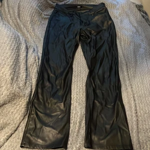 Svarta skinnbyxor från Bik Bok - Snygga svarta byxor i skinnimitation från Bik Bok. Byxorna har en rak passform och låg midja, vilket ger en trendig look. Perfekta att styla med en enkel topp eller stickad tröja. Materialet är mjukt och följsamt.