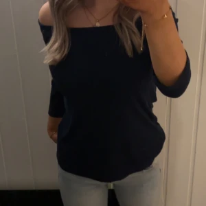 Mörkblå offshoulder topp - Säljer en mörkblå offshoulder topp med rak halsringning från Ginatricot. Toppen har trekvarts ärmar och en enkel, stilren design som passar perfekt till jeans eller kjol.