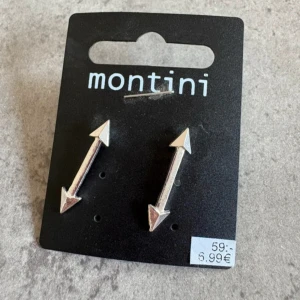 Silvriga pilformade örhängen från Montini - Säljer ett par silvriga örhängen från Montini i form av pilar. Snygg och stilren design som passar perfekt för att ge din look en extra edge. Oanvända 