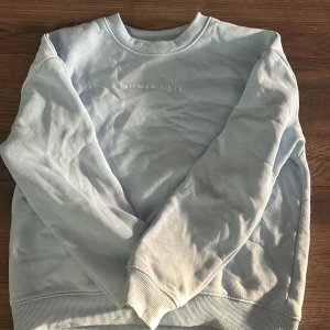 Ljusblå sweatshirt med broderad text - Säljer en ljusblå sweatshirt med broderad text 'summer vibes' på bröstet. Tröjan har rund halsringning och långa ärmar med ribbade muddar. Perfekt för en avslappnad stil.