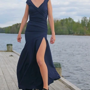 Mörkblå balklänning💙 -  Såå fin balklänning, endast använd en gång!                -Vävt, något stretchigt material. - Öppen halsringning. - Figurnära omlottdesign upptill. - Vid kjol med hög slits. - Dold dragkedja i ryggen. - Bra längd på mig som är 174 cm