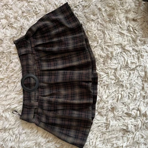 Brun rutig kortkjol med bälte - Snygg brun rutig kortkjol med ett brett bälte och stor ringdetalj. Perfektför våren, skriv vid frågor!🤗