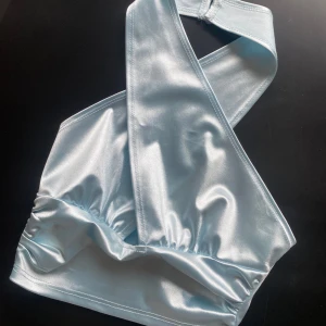 Ljusblå halterneck topp - Snygg ljusblå halterneck topp i glansigt material. Aldrig använd men lappen är borttagen storlek xs