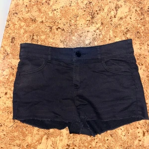 Svarta jeansshorts med rå kant - Snygga svarta jeansshorts med rå, fransig kant nertill och klassisk femficksdesign. Shortsen har knapp och dragkedja framtill samt bälteshällor. Perfekta för varma dagar och en chill look.
