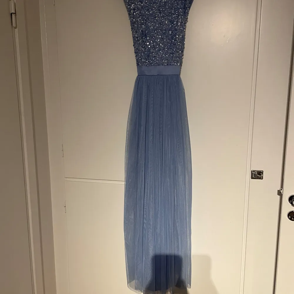 Säljer en ljusblå långklänning med glittrig paljettöverdel och djup v-ringad rygg. Kjolen är i tunt, flowy tyg som ger en elegant känsla. Perfekt för bal eller fest! 💙. Mekot.