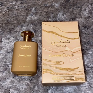 Caramel Cascade Parfym från Paris Corner - Upptäck Caramel Cascade från Paris Corner, en lyxig parfym med toppnoter av karamell och mjölk, hjärtnoter av tonkaböna och honung, samt basnoter av vanilj och vit mysk. Flaskan har en elegant beige färg med gyllene detaljer och en stilren design.