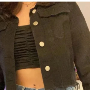 Svart croppad jacka med knappar - Snygg svart croppad jacka med knappar framtill. Perfekt för en trendig look. Jackan har en stilren design och är lätt att matcha med olika outfits.