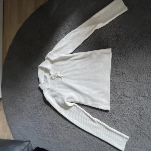 Vit ribbad tröja från Maison Meilene - Säljer en stilren vit ribbad tröja från Maison Meilene. Tröjan har långa ärmar och en snygg snörning vid halsen som ger en unik touch. Knappt använd. Lite mindre i storleken så passar nog bättre för folk som har storlek S. 