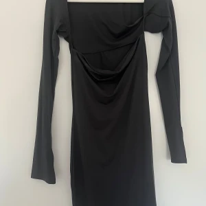Grå klänning  - Mörkgrå klänning från Gina Tricot men en bandeu liknande överdel fast med långa ärmar men en liten slits i slutet. Aldrig använd. På mig som är 170cm så går den ner till mitten på låren. Storlek S. 200kr.