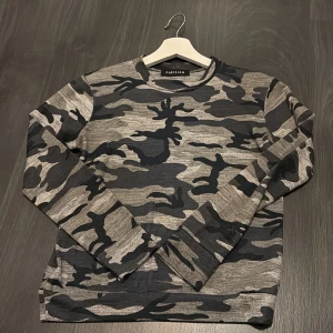 Camo-mönstrad långärmad tröja från Parisian - Säljer en långärmad tröja från Parisian med grått och svart camouflage-mönster. Tröjan är i storlek S. tror jag köpte den på Nelly men lite oklart. Den är lite nopprig här o var men ingenting som syns skulle jag säga.