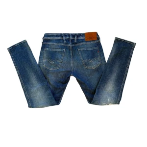 Blå Replay Jeans - Snygga blå jeans från Replay med en cool slitningseffekt. De har en klassisk femficksdesign och en knappgylf. Perfekta för en avslappnad stil med en touch av edge. Dem är i modellen Anbass Hyperflex och är svåra att få tag på med dessa slitningar‼️Skriv gärna frågor eller skicka prisförslag till mig😇