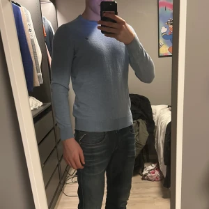 Ljusblå tröja från Morris - Säljer en stilren ljusblå tröja från Morris. Tröjan har en liten broderad logga på bröstet och är tillverkad i merinoull, den är storlek L men sitter som s/m, nypris 1500kr.