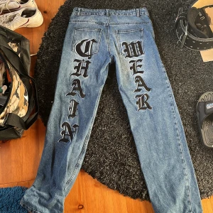 Blå jeans med tryck - Snygga blå jeans med stort tryck 'CHAIN WEAR' i svart på benen. De är i mycket bra skick utan hål och andra fel. Säljer för har bytt stil! Pris kan diskuteras!