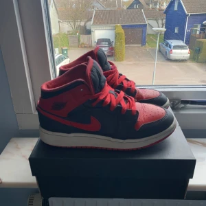 Nike Air Jordans i svart och rött - Snygga Nike Air Jordans i klassisk svart och röd färgkombination. Skorna har en ikonisk design med röd snörning och den välkända Jumpman-loggan på plösen. Perfekta för dig som vill ha en stilren och sportig look.