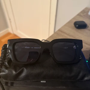 Svarta solglasögon från Off-White - Snygga svarta solglasögon från Off-White med en fyrkantig form och märkets ikoniska logotyp på skalmarna. Tillverkade i Italien, dessa glasögon är både stilrena och trendiga.