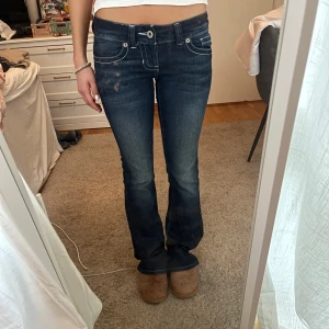 Lågmidjade bootcut jeans från Guess - Snygga lågmidjade mörkblå jeans från Guess med coola vita sömmar som detaljer! Knappt använda💕💕 kom privat för mer mått❤️