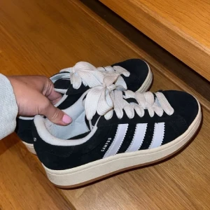 Svarta sneakers med vita ränder - Snygga svarta sneakers med vita ränder och snörning. Perfekta för en avslappnad stil. De har en klassisk design med en bekväm sula.