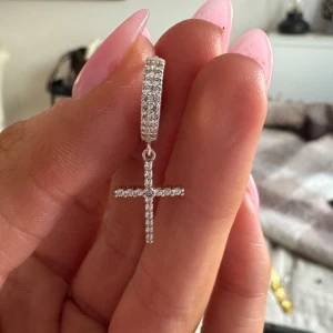 Silverörhänge med korshänge - Säljer detta superfina öronhänget med silvriga stenar och ett hängande kors. Använt endast en gång! Köpt från L8hasselblad💕💕 
