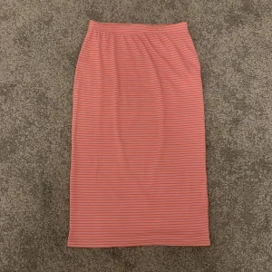 Rosa randig kjol från Vero Moda - Snygg rosa kjol med orangefärgade ränder från Vero Moda. Kjolen är knälång och har super skönt material. Storlek xs.