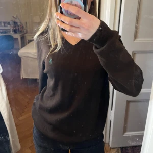 Brun tröja från Polo Ralph Lauren - Säljer en stilren brun tröja från Polo Ralph Lauren med v-ringning och det klassiska logotypbroderiet på bröstet. Perfekt för en avslappnad och elegant look. Tröjan har långa ärmar och är tillverkad i 100% bomull. Väldigt mjuk.