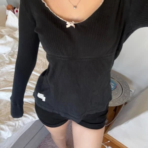 Svart ribbad tröja med rosett - Säljer en svart ribbad tröja från odd molly i storlek s.