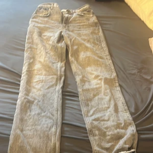 Grå jeansbyxor - Säljer ett par grå jeansbyxor med en klassisk design. Byxorna har en rak passform och är perfekta för en avslappnad stil. De har fickor fram och bak samt en dragkedja och knapp i midjan.