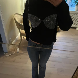 Svart tröja med glittrig detalj - Säljer en svart tröja med en unik glittrig detalj framtill. Tröjan har långa ärmar och en normal passform. Perfekt för att lägga till lite bling i vardagen. Hör av dig vid intresse! ✨ STORLEK - XL PRIS går att diskutera! Skriv om du har frågor 🫶🤍