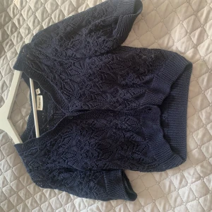 Svart kofta från Kappahl - Säljer en snygg marinblå kofta från Kappahl med ett fint stickat mönster. Koftan har trekvartsärmar och knappar framtill. Knappt använd