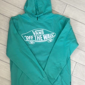 Hoodie från Vans - Säljer en hoodie från Vans med det klassiska 'Off The Wall' trycket i vitt på framsidan. Tröjan har en bekväm passform med långa ärmar och en praktisk huva. Perfekt för en avslappnad stil!