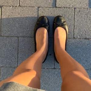 Svarta ballerinaskor med rosett - Snygga svarta ballerinaskor med en liten rosett på ovansidan. Perfekta för en stilren look och bekväma att bära hela dagen. Väldigt små i storleken. 